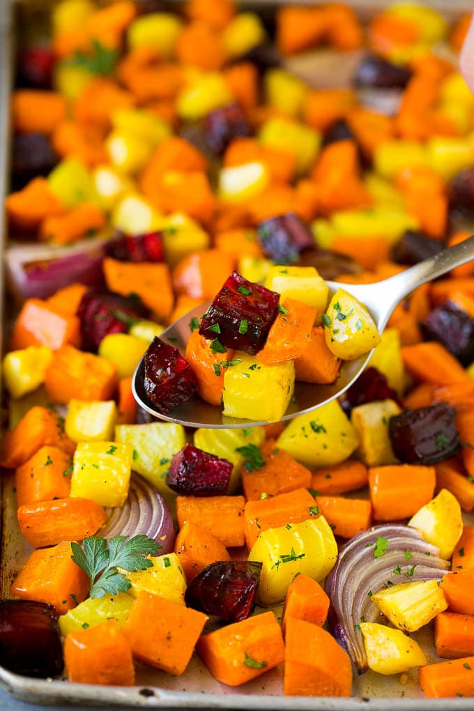 Roasted Root Vegetables Recipe | Roasted Sweet Potatoes | Roasted Beets | Roasted Carrots #carrots #beets #vegetables #sweetpotatoes #fall #parsnips #sidedish #bajap #cleaneating #healthy A spoon serving up a portion of roasted vegetables.