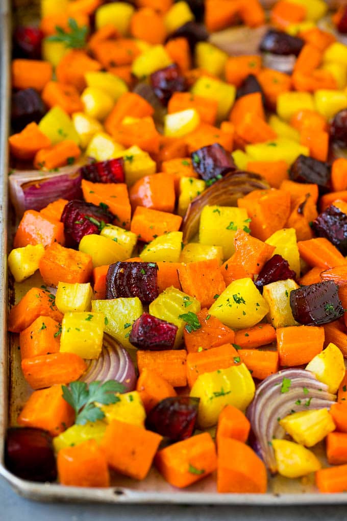 Roasted Root Vegetables Recipe | Roasted Sweet Potatoes | Roasted Beets | Roasted Carrots #carrots #beets #vegetables #sweetpotatoes #fall #parsnips #sidedish #bajap #cleaneating #healthy Roasted root vegetables on a sheet pan, topped with chopped parsley.