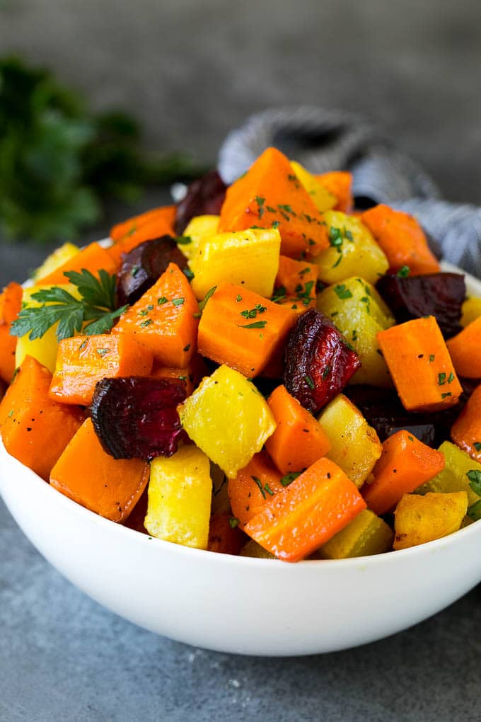 Roasted Root Vegetables Recipe | Roasted Sweet Potatoes | Roasted Beets | Roasted Carrots #carrots #beets #vegetables #sweetpotatoes #fall #parsnips #sidedish #bajap #cleaneating #healthy A bowl of diced roasted root vegetables topped with parsley.