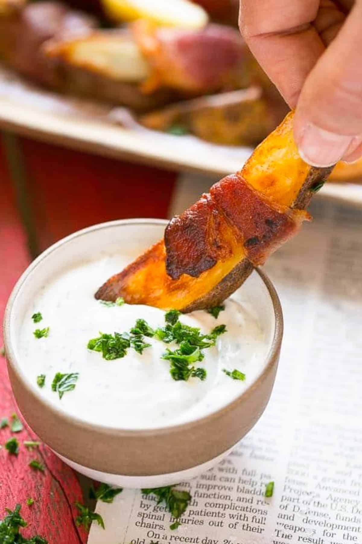 Bacon Wrapped Potato Wedges Recipe | Best Potato Wedges | Bacon Wrapped French Fries | Bacon Potato Wedges #bacon #potato #fries #dinner #bajap A hand putting bacon wrapped potatoes into ranch dip.