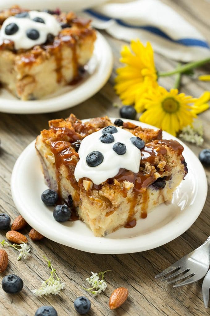 Blueberry Bread Pudding Recipe | Blueberry Bread Pudding | Easy Bread Pudding #blueberry #breadpudding #dessert #bajap Slices of bread pudding on plates, topped with caramel and fresh berries.