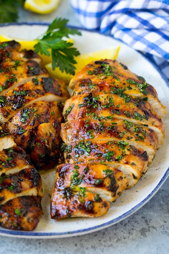 Grilled Chicken Breast Recipe | Marinated Chicken Breast | Chicken Marinade #chicken #grilling #marinade #summer #dinner #bajap Sliced grilled chicken breast garnished with herbs and lemon.