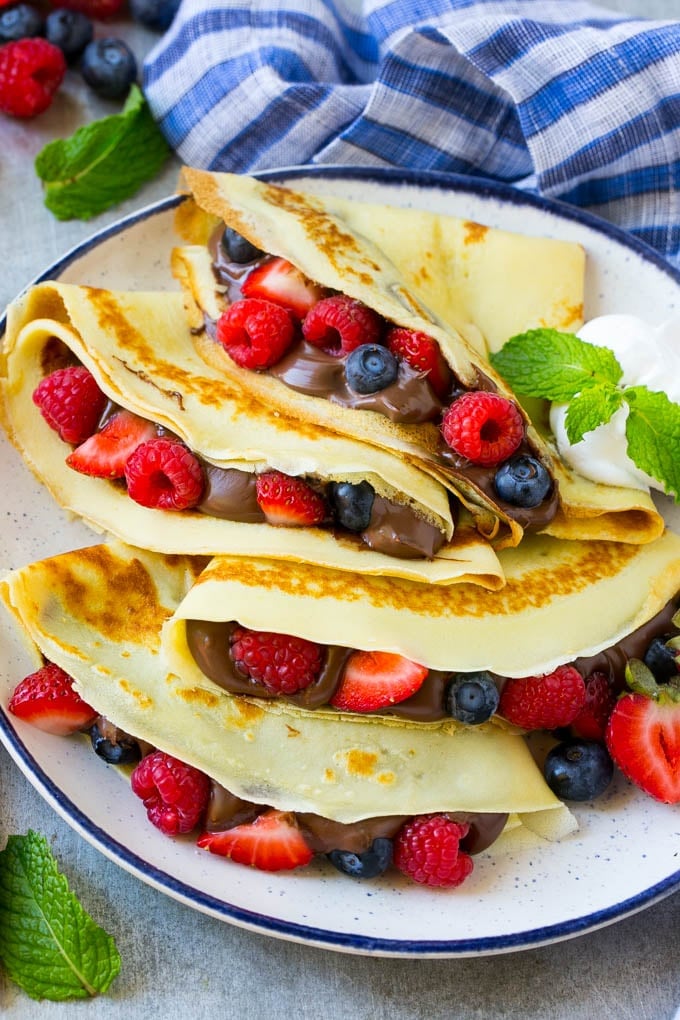 Nutella Crepes Recipe | Easy Crepes Recipe | Blender Crepes | Berry Crepes #crepes #nutella #nutellacrepes #blendercrepes #breakfast #bajap A platter of crepes served with whipped cream.