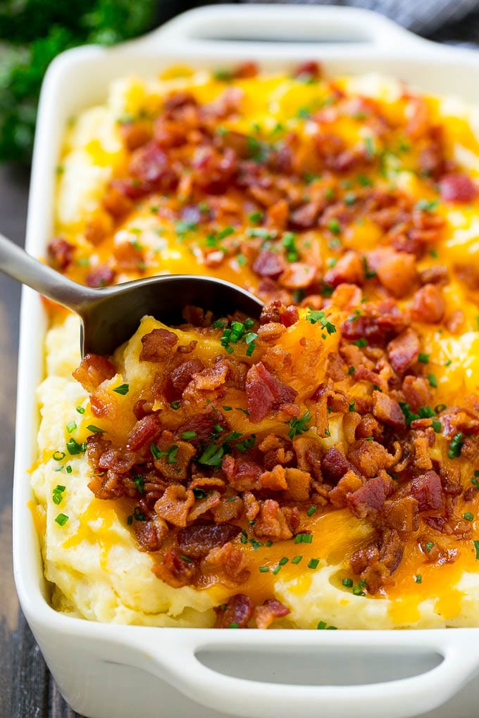 Loaded Mashed Potato Casserole Recipe | Loaded Potatoes | Bacon Mashed Potatoes | Thanksgiving Mashed Potatoes #potatoes #bacon #cheese #casserole #Thanksgiving #dinner #bajap A dish of loaded mashed potato casserole with a serving spoon in it.