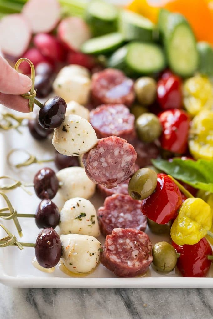 Antipasto Skewers Recipe | Easy Antipasto | Best Antipasto #antipasto #skewers #appetizer #bajap A hand holding up a skewer of salami, cheese and olives.