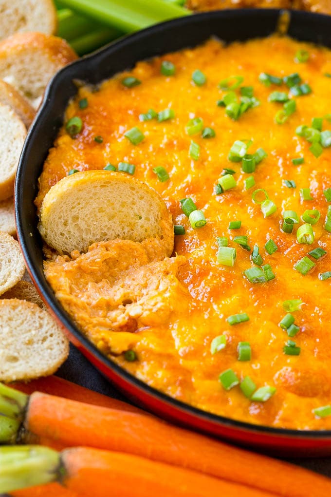 Buffalo Ranch Chicken Dip | Buffalo Chicken Dip | Baked Buffalo Dip | Cheesy Buffalo Dip #buffalowings #buffalochicken #dip #lowcarb #appetizer #bajap Buffalo ranch chicken dip with a baguette slice in it.