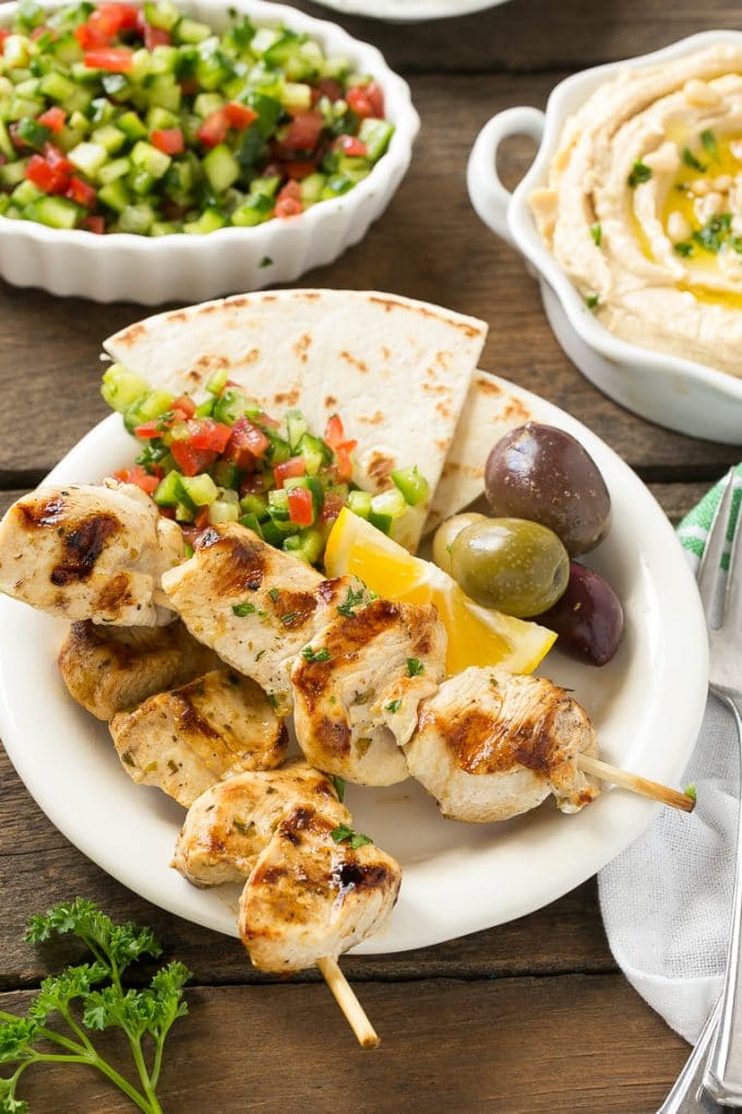 Greek Chicken Souvlaki Recipe | Easy Greek Chicken | Chicken Souvlaki | Greek Chicken Skewers | Easy Greek Chicken Skewers #chicken #kabobs #glutenfree #keto #lowcarb #grilling #bajap A plate of skewers with olives and pita bread.