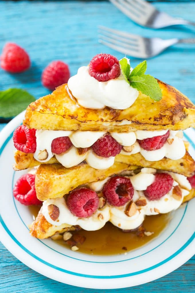 Stuffed French Toast | Cream Cheese Stuffed French Toast | French Toast Recipe #frenchtoast #raspberry #creamcheese #breakfast #brunch #bajap A plate of cooked brioche filled with cream cheese, berries and almonds.