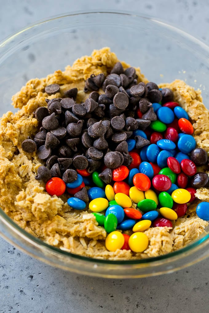 Monster Cookies Recipe | Oatmeal Cookies | Peanut Butter Cookies | M&M's Cookies #baking #cookies #dessert #peanutbutter #chocolate #bajap Cookie dough with chocolate chips and M&M's on top.