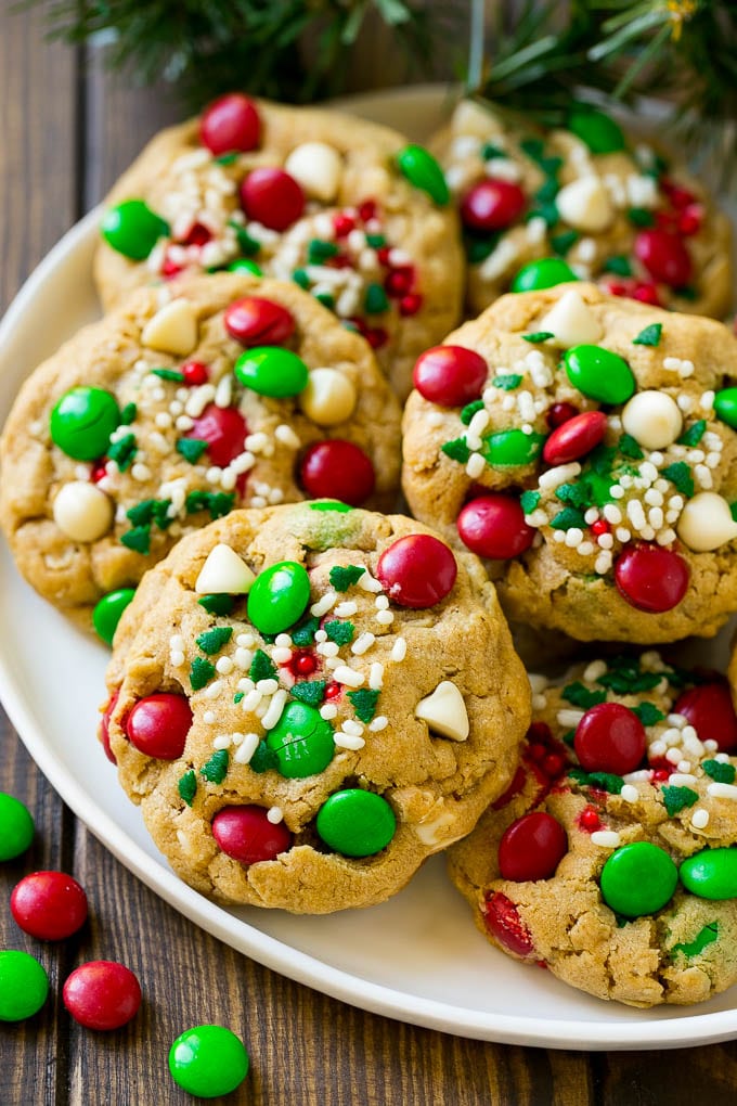 Christmas Monster Cookies Recipe | Oatmeal Cookies | Peanut Butter Cookies | M&M's Cookies #baking #cookies #dessert #peanutbutter #chocolate #bajap #christmas #sprinkles A plate of Christmas monster cookies which are decorated with M&M's, white chocolate and sprinkles.