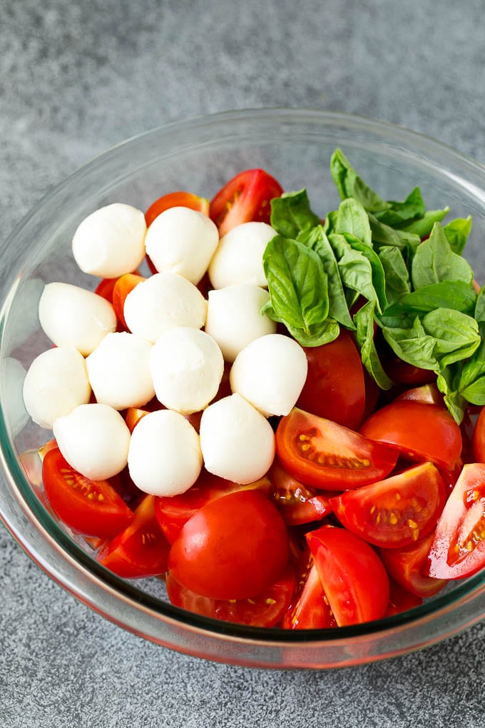 Caprese Salad Recipe | Tomato Salad #salad #tomato #mozzarella #cheese #basil #caprese #summer #bajap Tomatoes, mozzarella and basil in a bowl.