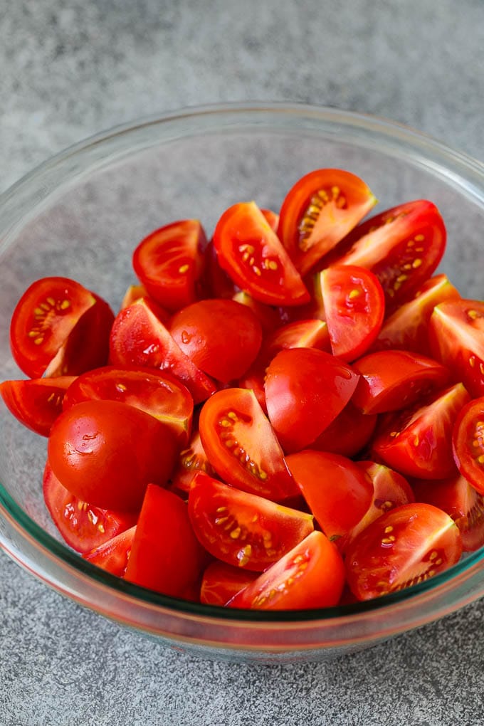 Caprese Salad Recipe | Tomato Salad #salad #tomato #mozzarella #cheese #basil #caprese #summer #bajap Quartered tomatoes in a bowl.