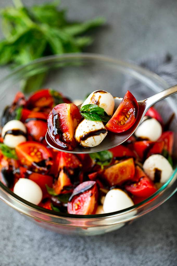 Caprese Salad Recipe | Tomato Salad #salad #tomato #mozzarella #cheese #basil #caprese #summer #bajap A serving spoon of caprese salad with tomato, mozzarella and basil.
