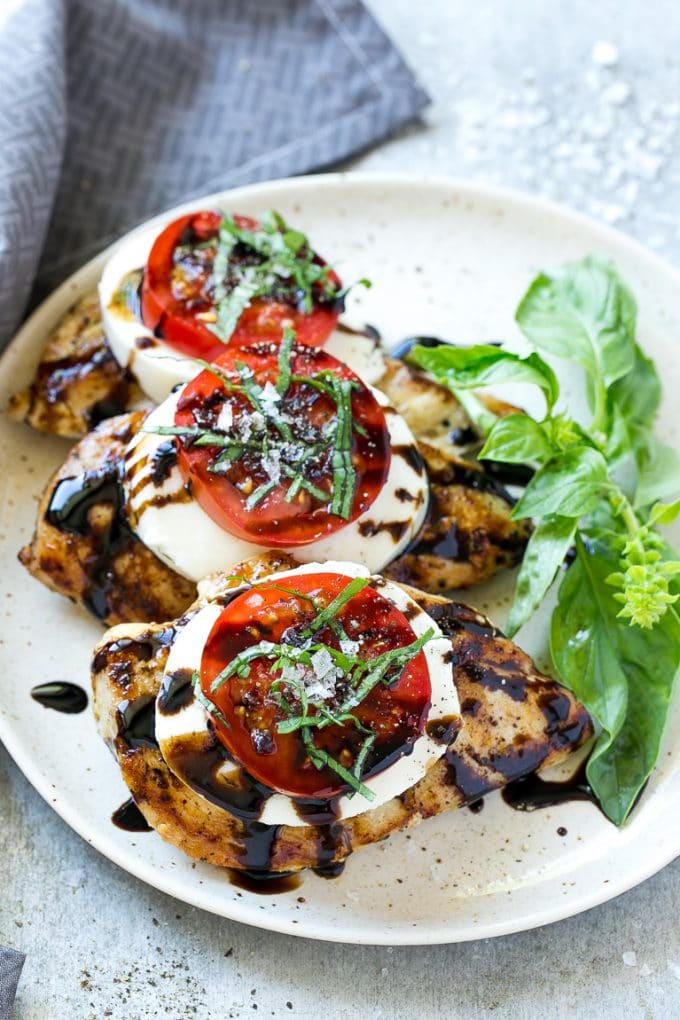 Chicken Caprese Recipe | Grilled Chicken #chicken #caprese #grilling #dinner #tomato #basil #bajap Grilled chicken on a serving plate topped with sliced tomato and cheese.