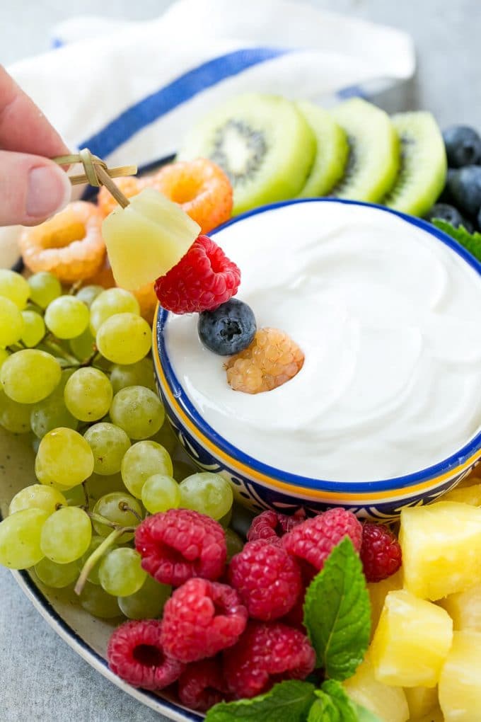 Cream Cheese Fruit Dip | Fruit Recipe | Fruit Dip #fruit #dip #creamcheese #snack #dessert #bajap A skewer of berries going into a bowl of fruit dip.