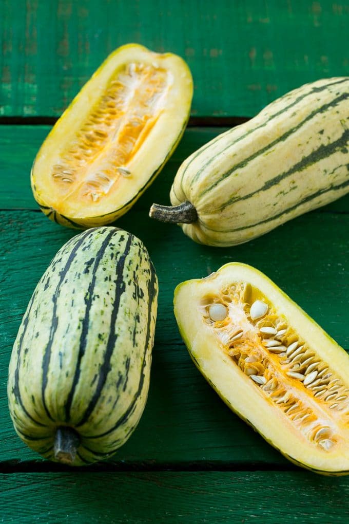 Brown Sugar Delicata Squash Recipe | Roasted Squash | Delicata Squash | Winter Squash Recipe #squash #wintersquash #brownsugar #sidedish #delicatasquash #dinner #bajap Raw delicata squash on a green board.