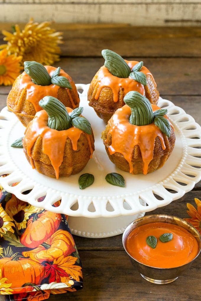 Pumpkin Spice Cake Recipe | Pumpkin Cake | Easy Pumpkin Cake | Thanksgiving Dessert #thanksgiving #pumpkin #cake #pumpkincake #spicecake #dessert #bajap #holiday Pumpkin spice cake topped with orange glaze and fondant decorations on a serving platter.