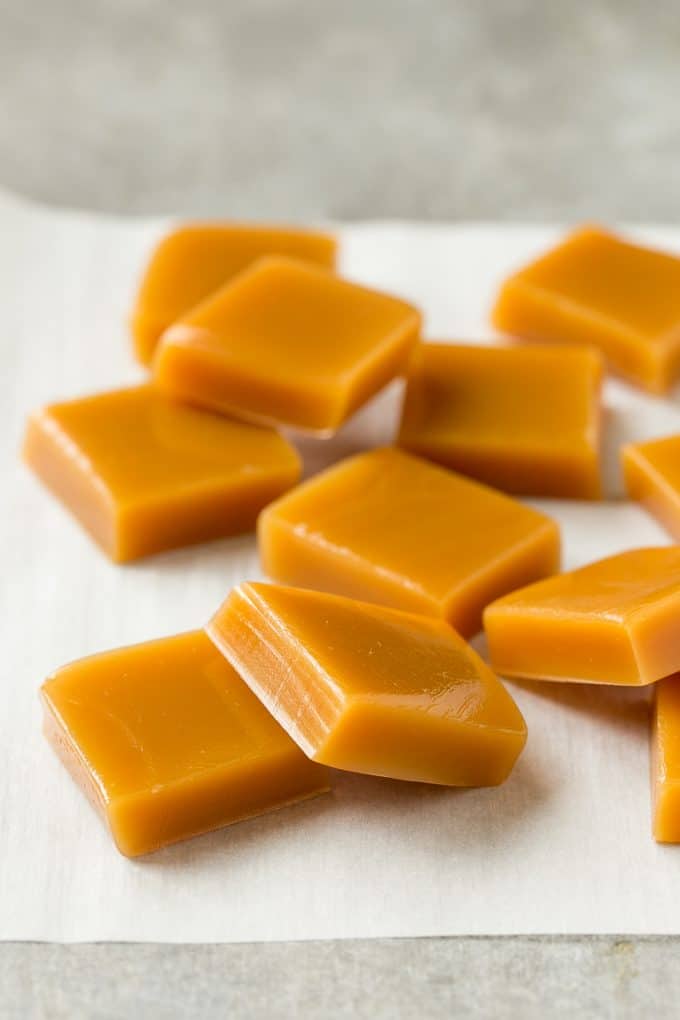 Microwave Caramels with Sea Salt Recipe | Homemade Caramels | Sea Salt Caramel | Homemade Candy #candy #caramels #caramel #microwavecaramels #homemade #dessert #bajap Squares of cooked caramel on parchment.