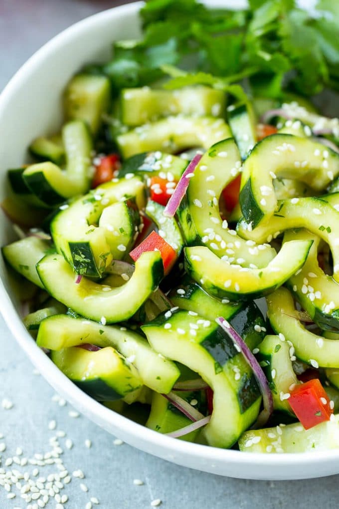 A bowl of Asian cucumber salad with dressing and sesame seeds on top.