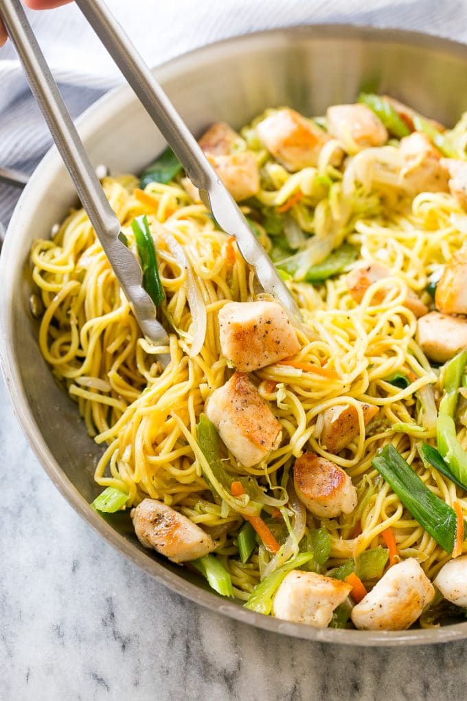 Chicken Chow Mein Recipe | Easy Chicken Recipe | Chow Mein | Chinese Food #chowmein #takeout #asianfood #bajap A pan of chicken chow mein with tongs pulling out a serving.