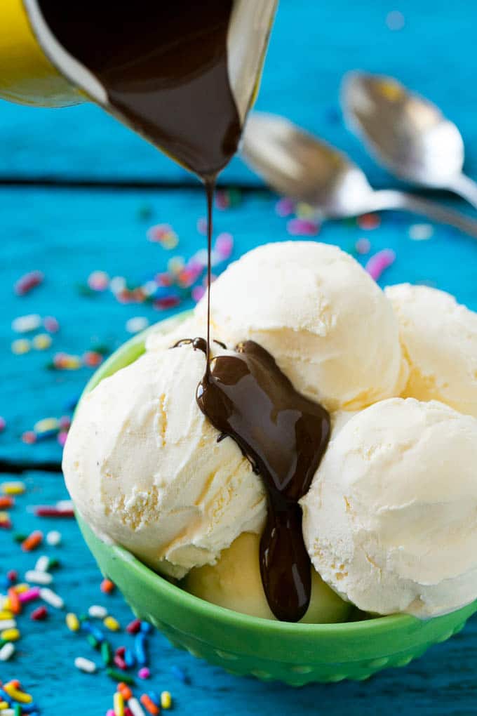 Homemade Magic Shell Recipe | Chocolate Ice Cream Topping | Chocolate Sauce | Hard Chocolate Coating #chocolate #icecream #dessert #bajap A pitcher of chocolate sauce being poured over vanilla ice cream.