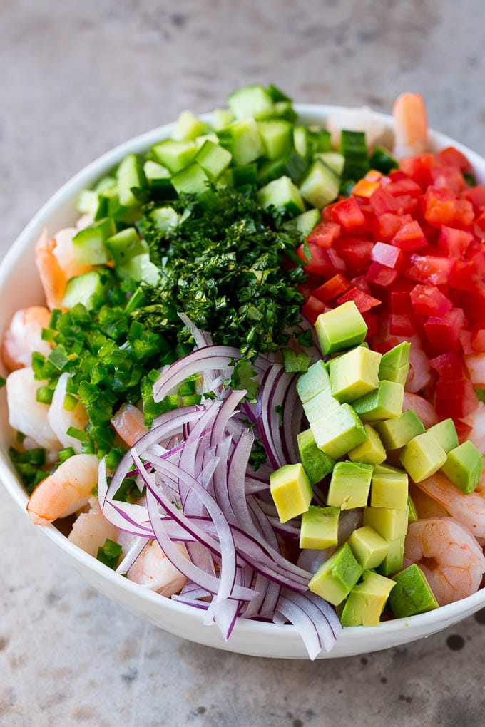 Shrimp Ceviche Recipe | Mexican Shrimp | Marinated Shrimp #shrimp #ceviche #cleaneating #healthy #lowcarb #keto #glutenfree #dinner #appetizer #bajap Prawns, avocado, red onion tomatoes, cilantro, jalapeno and cilantro in a bowl.