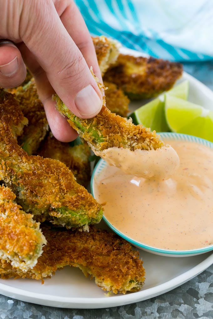 Avocado Fries Recipe | Fried Avocado | Avocado Fritters #avocado #appetizer #snack #bajap A hand dipping an avocado fry into sauce.