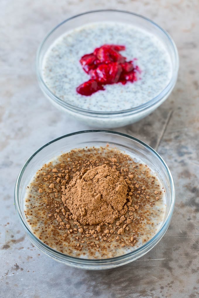 Bowls of chia pudding, one with cocoa powder on top and the other with crushed raspberries.