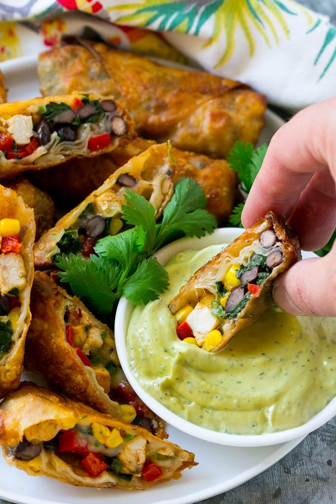 Southwestern Egg Rolls Recipe | Easy Egg Roll Recipe | Mexican Appetizer | Egg Roll Recipe | Southwest Egg Rolls #eggrolls #appetizer #chicken #snack #bajap A southwestern egg roll being dipped into avocado sauce.