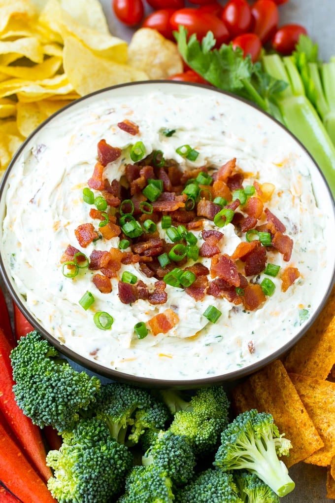 Bacon Ranch Dip Recipe | Homemade Ranch Dip | Easy Dip Recipe | Cheddar Ranch Dip #ranch #ranchdip #bacondip #dip #snack #bajap #baconranchdip A bowl of creamy bacon cheddar ranch dip surrounded by vegetables and chips.