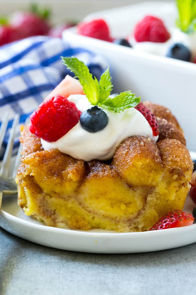 Donut Bread Pudding Recipe | Easy Bread Pudding | Cinnamon Donuts | Make Ahead Breakfast Recipe #breadpudding #donuts #donutholes #breakfast #bajap Slice of donut bread pudding topped with whipped cream and berries.