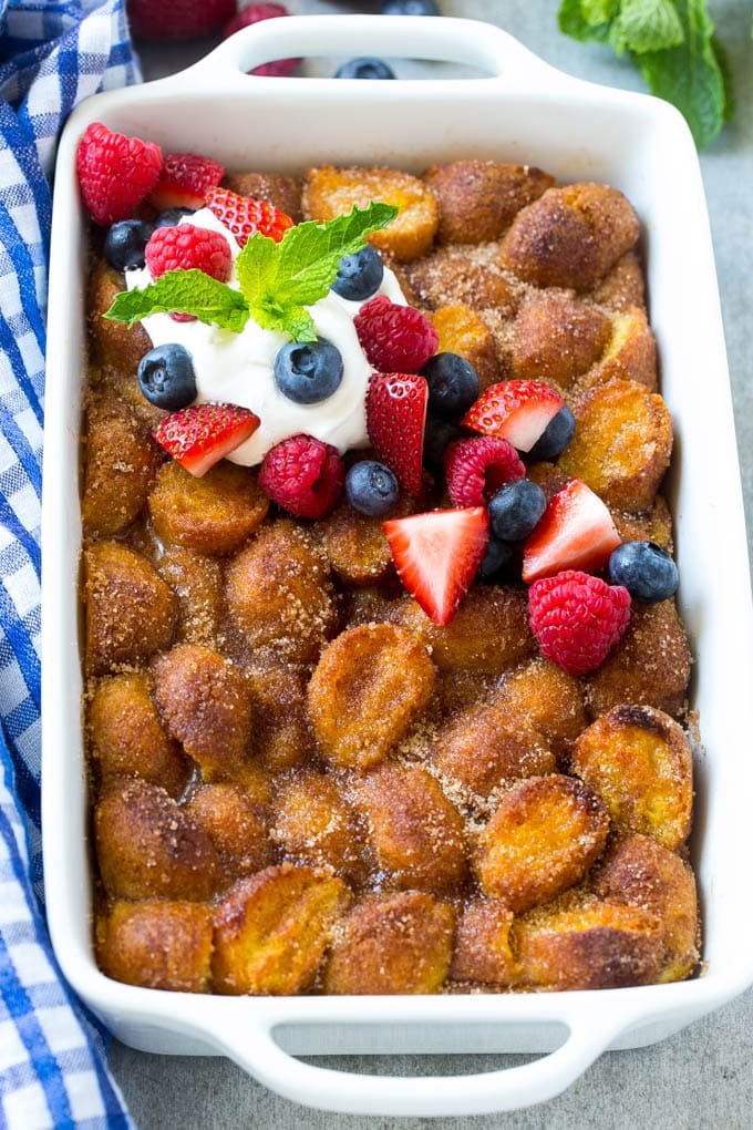 Donut Bread Pudding Recipe | Easy Bread Pudding | Cinnamon Donuts | Make Ahead Breakfast Recipe #breadpudding #donuts #donutholes #breakfast #bajap A tray of donut bread pudding garnished with whipped cream and berries.