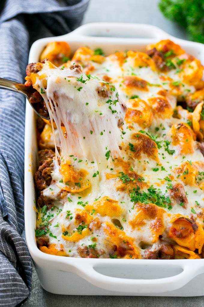 Baked Tortellini with Meat Sauce Recipe | Cheese Tortellini | Tortellini Recipe | Baked Pasta Recipe #tortellini #bakedtortellini #meatsauce #pasta #dinner #bajap A pan of cheesy baked tortellini with a spoon lifting up a portion.