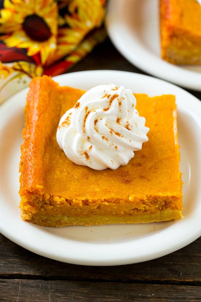 Pumpkin Gooey Butter Cake Recipe | Pumpkin Cake Recipe | Gooey Butter Cake | Pumpkin Dessert | Thanksgiving Dessert #pumpkin #cake #pumpkincake #gooeybuttercake #dessert #bajap A slice of pumpkin gooey butter cake topped with whipped cream.