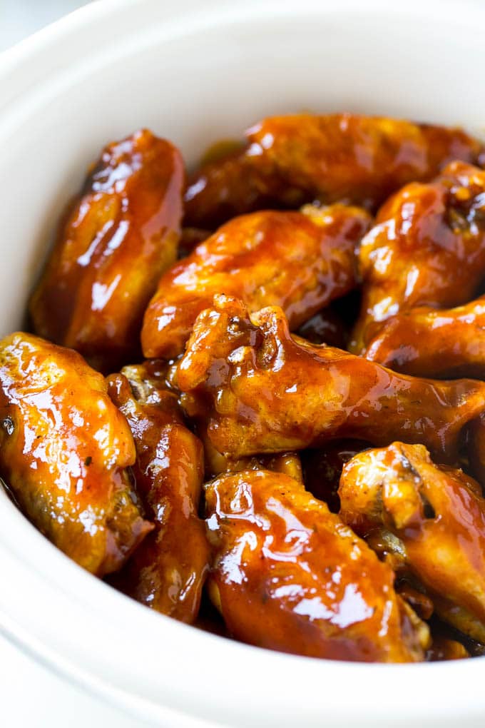 Slow Cooker Barbecue Chicken Wings | Crock Pot Chicken Wings | Barbecue Chicken Wings | Easy Chicken Wings #chickenwings #slowcooker #crockpot #bbqchicken #partywings #appetizer #bajap Slow cooker chicken wings coated in sauce in a white crock pot.