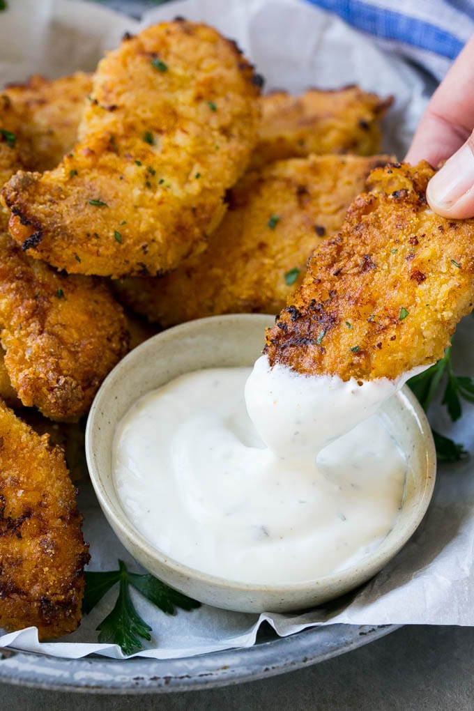 Baked Fried Chicken Recipe | Oven Fried Chicken | Baked Chicken Fingers | Crispy Chicken Fingers #chicken #friedchicken #bakedchicken #ovenfriedchicken #chickenfingers #dinner #bajap A chicken finger being dipped into ranch dressing.