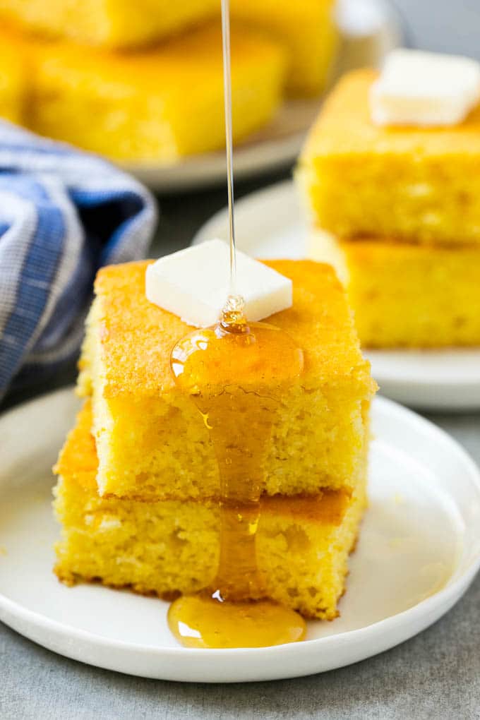 Honey Cornbread Recipe | Buttermilk Cornbread | Easy Cornbread | Homemade Cornbread | Cast Iron Cornbread #cornbread #honey #buttermilk #bread #bajap A stack of cornbread topped with butter and honey