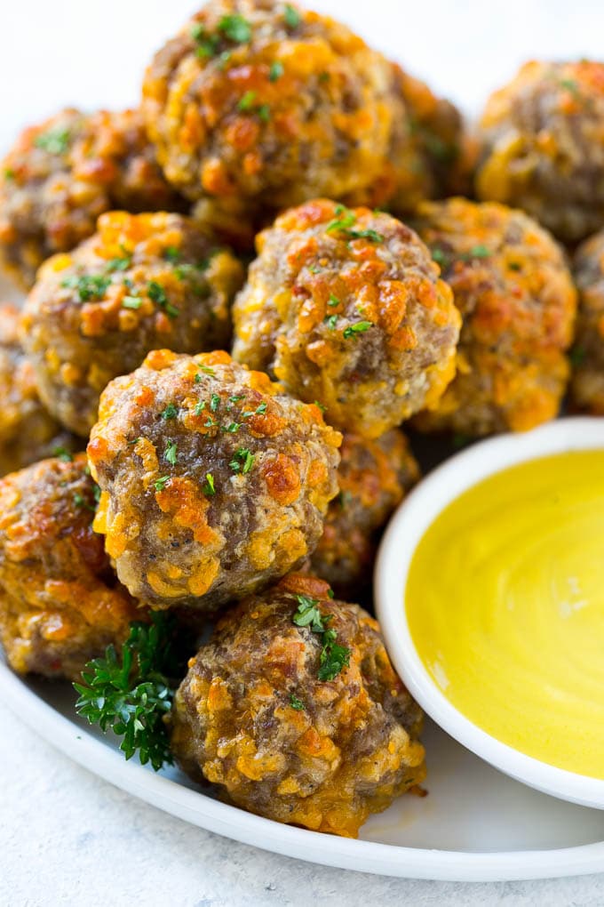 Sausage Cheese Balls Recipe | Sausage Balls Recipe | Bisquick Sausage Balls #sausage #sausageballs #balls #appetizer #cheeseballs #bajap A pile of sausage cheese balls with a side of honey mustard.
