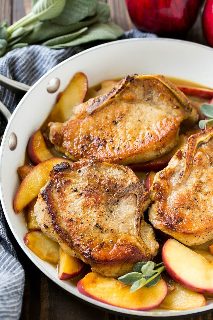 Apple Pork Chops Recipe | Pork Chops with Apples | Cider Pork Chops | Bone In Pork Chops Recipe #pork #porkchops #fall #apple #dinner #bajap A pan of apple pork chops garnished with fresh sage.