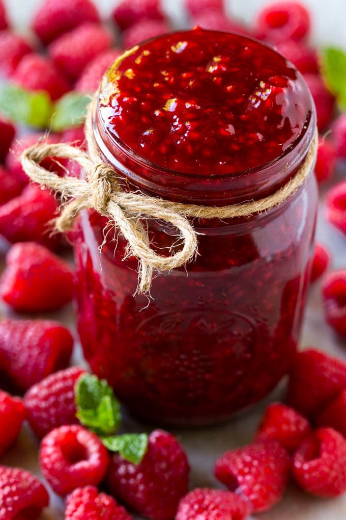 Raspberry Sauce Recipe | Homemade Raspberry Sauce | Raspberry Recipe #raspberries #dessert #bajap A jar of homemade raspberry sauce surrounded by fresh raspberries.