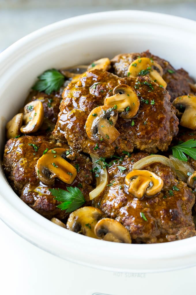 Slow Cooker Salisbury Steak Recipe | Homemade Salisbury Steak | Salisbury Steak from Scratch #steak #beef #salisbury #salisburysteak #slowcooker #crockpot #dinner #bajap A crock pot with hamburger patties, cooked mushrooms and gravy.
