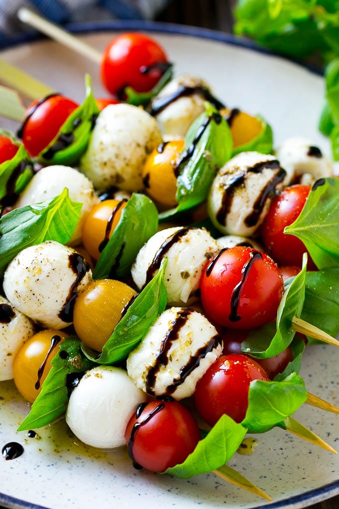 Caprese Skewers | Caprese Kabobs | Caprese Appetizer #tomato #mozzarella #basil #caprese #appetizer #bajap A plate of caprese skewers with mozzarella, tomatoes and basil.
