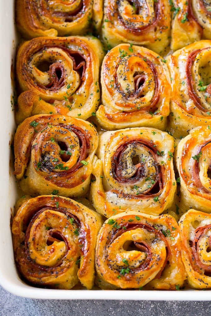 Ham and Cheese Pinwheels Recipe | Ham and Cheese Roll Ups | Ham and Cheese Rolls | Ham and Cheese Bread Rolls #ham #cheese #appetizer #pinwheels #bajap Ham and cheese pinwheels in a baking dish topped with parsley.