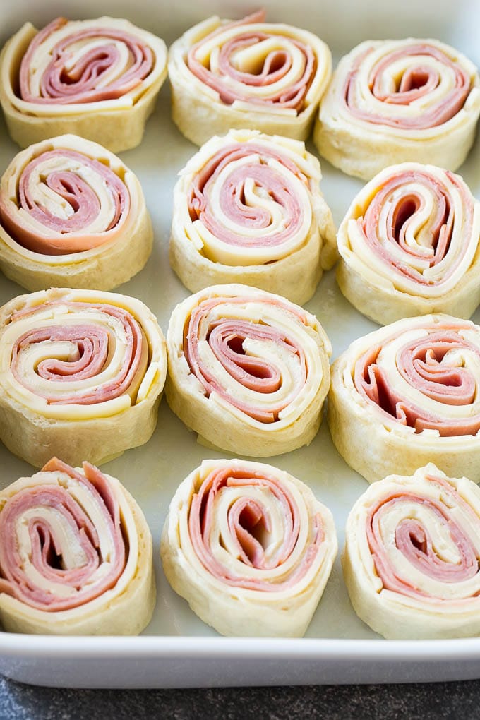 Ham and Cheese Pinwheels Recipe | Ham and Cheese Roll Ups | Ham and Cheese Rolls | Ham and Cheese Bread Rolls #ham #cheese #appetizer #pinwheels #bajap Rolled up ham, cheese and pizza dough circles in a baking dish.