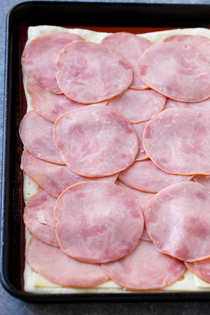 Ham and Cheese Pinwheels Recipe | Ham and Cheese Roll Ups | Ham and Cheese Rolls | Ham and Cheese Bread Rolls #ham #cheese #appetizer #pinwheels #bajap Slices of ham and cheese on top of dough.