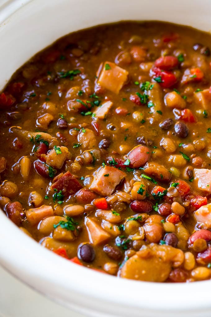Slow Cooker Ham Bone Soup | Ham and Bean Soup | Ham Bone and Bean Soup | Ham Soup | Leftover Ham Recipe #ham #hamsoup #leftoverham #soup #slowcooker #crockpot #bajap A slow cooker full of soup with parsley on top.
