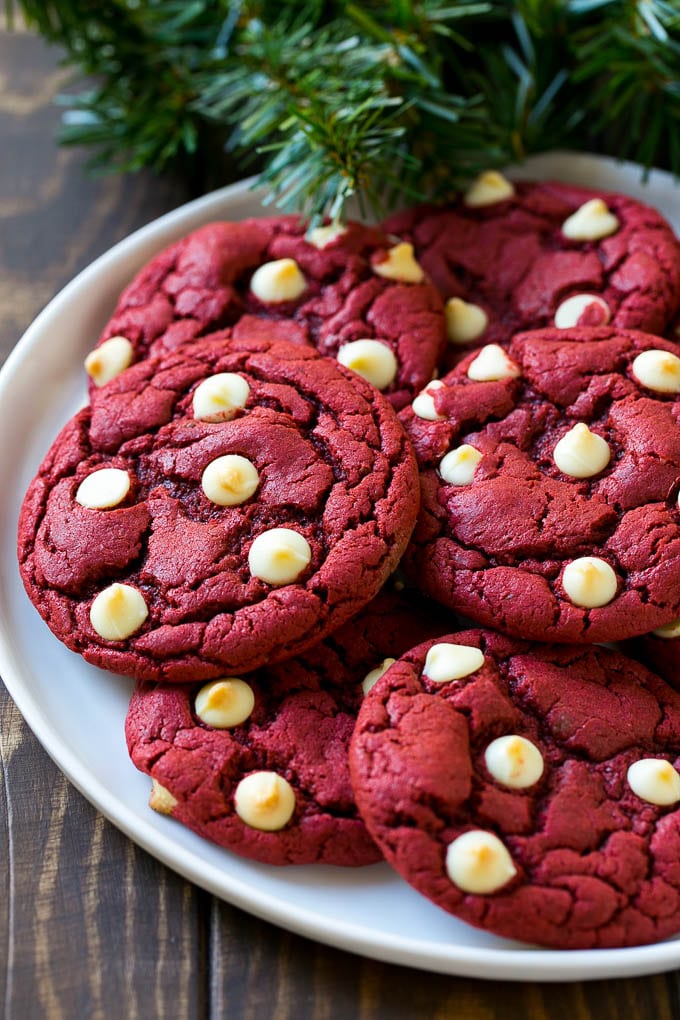 Red Velvet Cookies Recipe | Red Velvet Cookies with White Chocolate Chips | Red Velvet Cake Mix Cookies #redvelvet #cookies #whitechocolate #christmas #bajap Red Velvet Cookies on a serving plate with holiday decorations nearby,