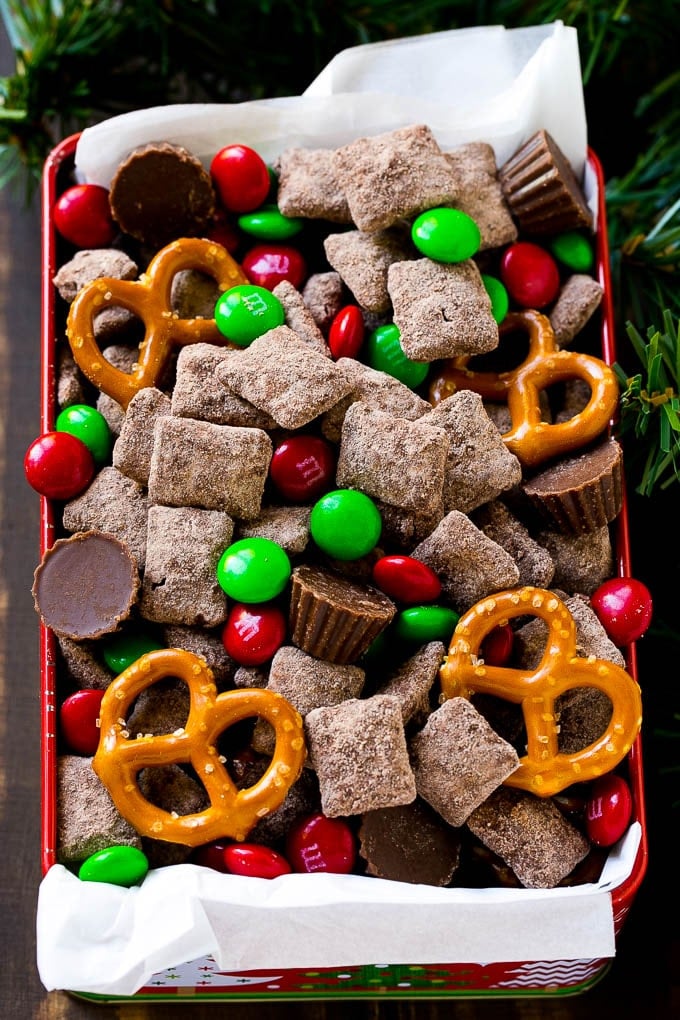 Reindeer Chow | Christmas Chex Mix | Christmas Muddy Buddies | Holiday Chex Mix #chex #chexmix #christmas #holiday #muddybuddies #reindeerchow #snack #bajap A tin of reindeer chow with chocolate coated chex, M&M's and pretzels.