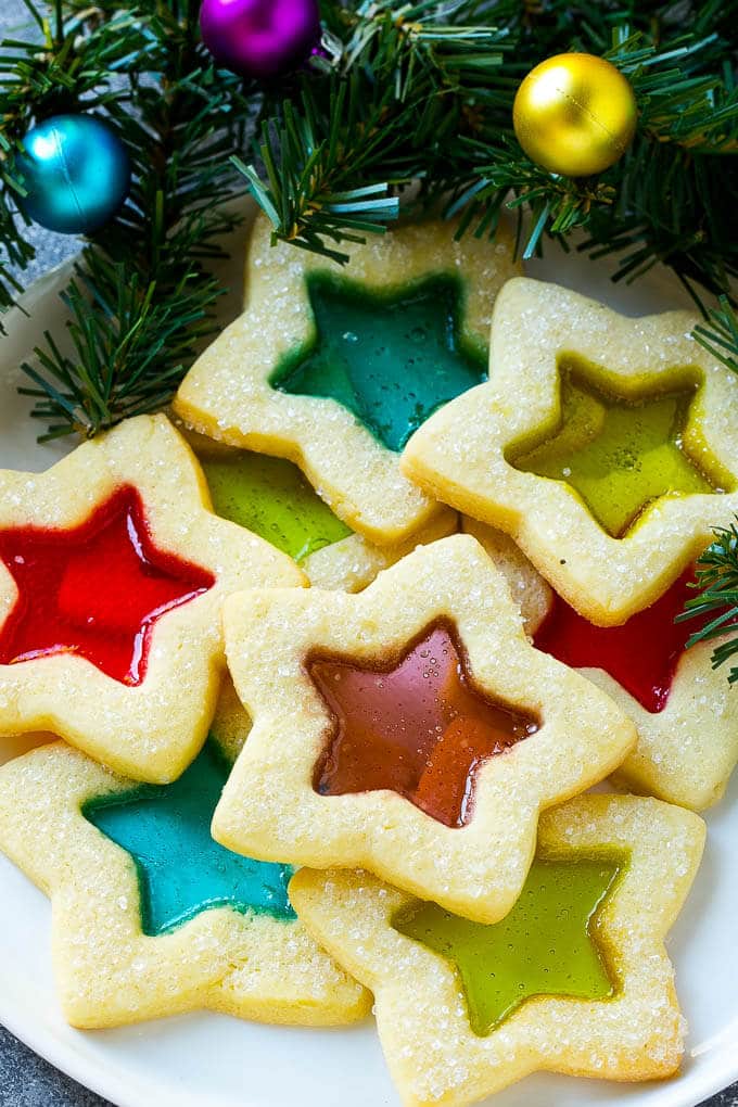Stained Glass Cookies | Stained Glass Window Cookies | Christmas Cookies | Sugar Cookies | Holiday Cookies #cookies #stainedglasscookies #sugarcookies #christmascookies #christmas #holiday #dessert #bajap A plate of star shaped stained glass cookies with colorful centers.