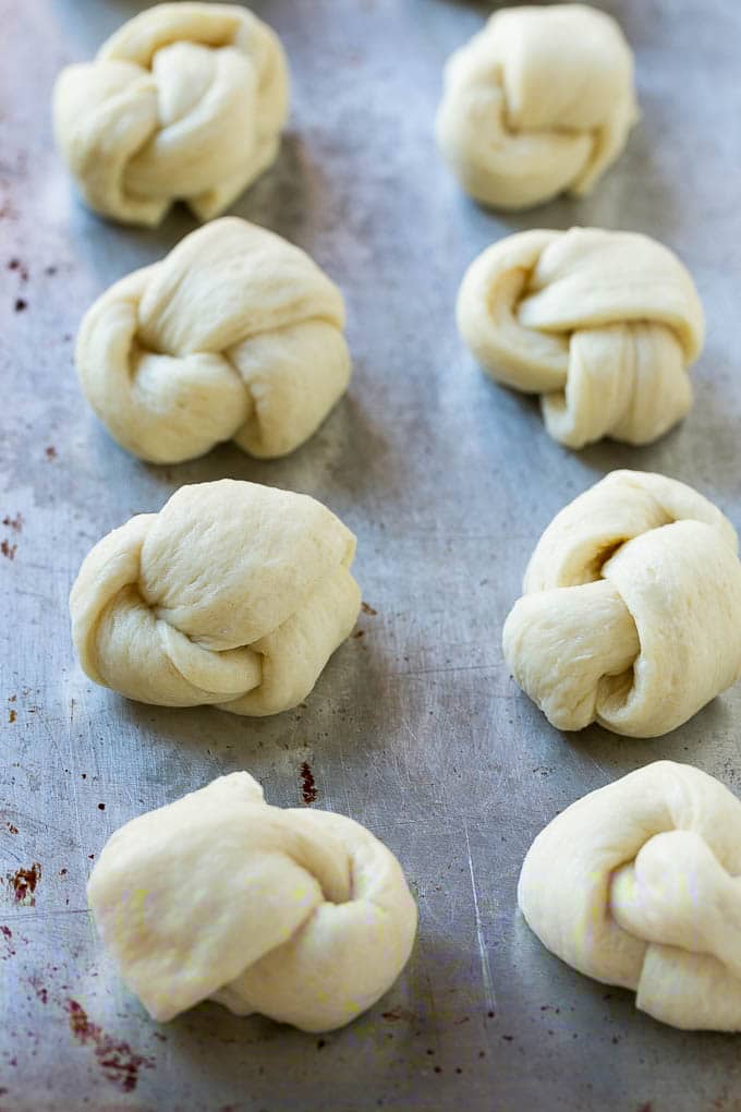 Garlic Knots Recipe | Garlic Rolls | Garlic Butter Rolls | Garlic Bread Recipe #garlic #garlicbread #garlicknots #breadsticks #bajap Pizza dough tied up and placed on a sheet pan.